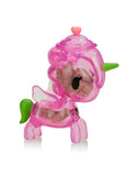 The tokidoki Sugar Shop Unicorno Blind Box features a pink translucent collectible with a green horn and tail, white wings, a heart on its head, and is filled with small brown blocks.