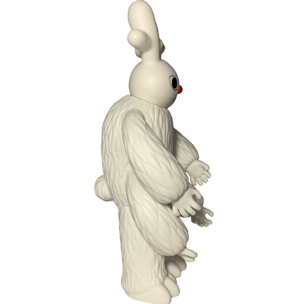 A side view of The Little Hut’s “Dream Monster - OG (White)”: a textured collectible figure with rabbit-like ears, a red nose, and large hands, standing upright against a plain background—reminiscent of characters from dreams.