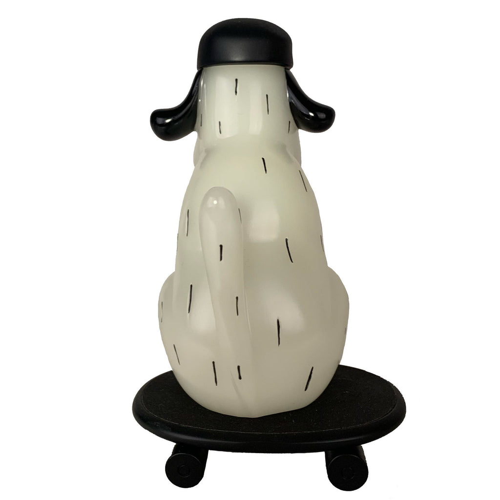 The How2Work One-Chu SK8 - Glow features a white dog figure with black ears and tail, sitting on a black round skateboard platform with wheels, shown from the back.