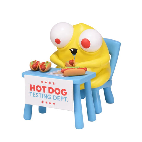 A cartoonish yellow creature with big eyes from Dead Zebra's "Hot Dog Tasting Dept." sits at a blue table, examining hot dogs under a sign strictly stating: ONE PER CUSTOMER.