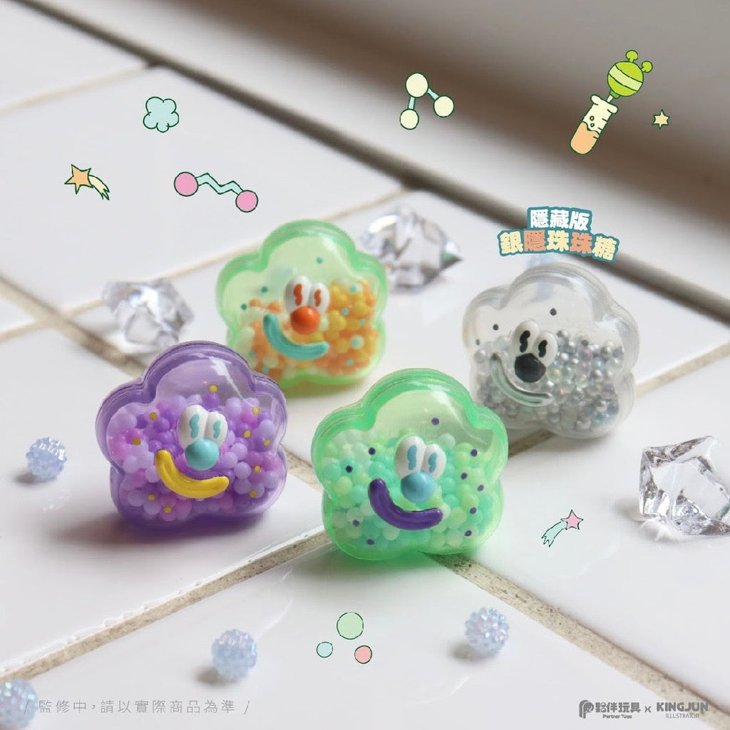 Four colorful cloud-shaped collectible figures with smiling faces and small beads inside from the Partner Toys KINGJUN Candy Lab Blind Box are displayed on a white surface with decorative crystals—ideal for fans of cute surprises.