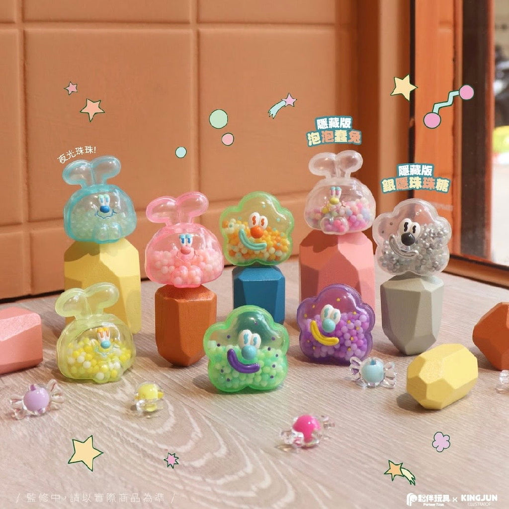 KINGJUN Candy Lab Blind Box containers by Partner Toys, shaped like animals and resembling collectible figures, are displayed on pastel geometric blocks near a window with small candy pieces scattered around.