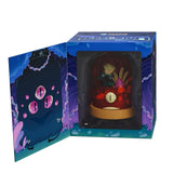 Kaleidos Creative’s Terrorium - Crab Cloche is a collectible window box figure featuring a dark forest scene with mushrooms and a creature sporting four glowing pink eyes, revealed beside an open flap in the display box.