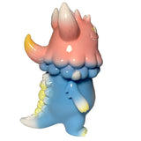 The Little Hut’s Rangeas Jr. - Light Blue/Pink features a pastel monster with a pink head, large horns, blue body, and yellow-tipped tail—an adorable collectible standing upright on a white background.