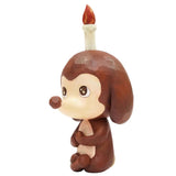 Keep Balance by How2Work is a whimsical brown cartoon dog figurine with a candle on its head, holding its knees and gazing sideways—perfect for adding charm and calm to your home decor.