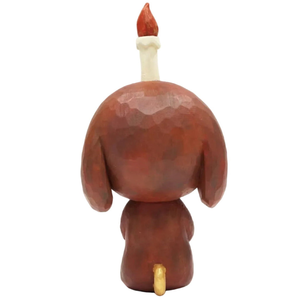 The Keep Balance meditation pup by How2Work is a stylized brown sculpture with a yellow tail and a lit candle on its head—ideal for adding balanced, soothing decor to your home.