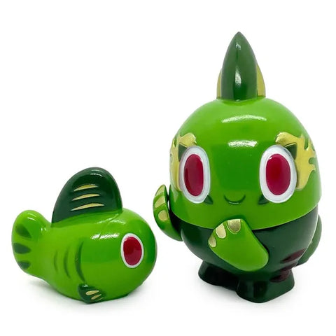 The Kibunadon Set- Green Tea by Teresa Chiba features two green fish-themed figures: one upright with arms and feet, the other a simpler fish shape lying on its side—a unique addition to any collection.