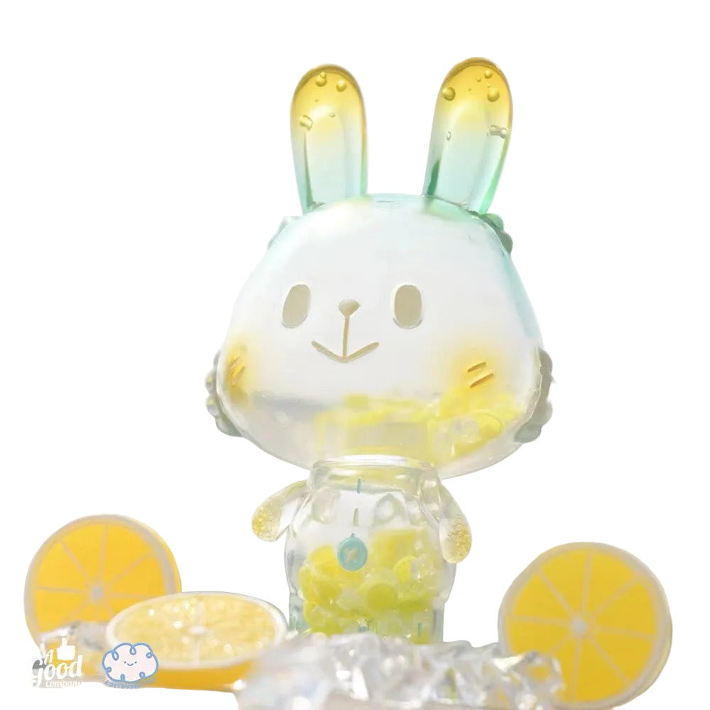 The Lemon Soda Robin by A Good Company is a translucent figurine with yellow-tipped ears and yellow beads inside, displayed among ice cubes and lemon slices—a charming and unique shelf ornament for your home decor.