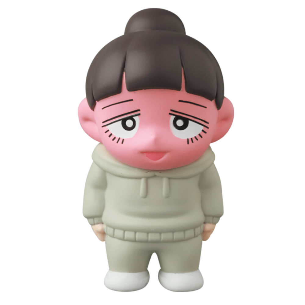 A pink-faced cartoon figure with dark hair in a bun, wearing a light gray hoodie and pants, stands against a white background—Medicom’s Vag 35 - Inu No Kagayaki is the perfect quirky office gift or playful desk decor.