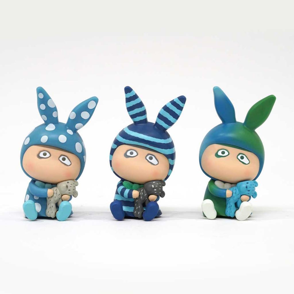 The How2Work A Boy — Mini Sitting Set features three mini figures by Hong Kong artist B. Wing in bunny-ear hats—blue polka dot, blue striped, and blue-green—each holding a toy animal against a plain white background.