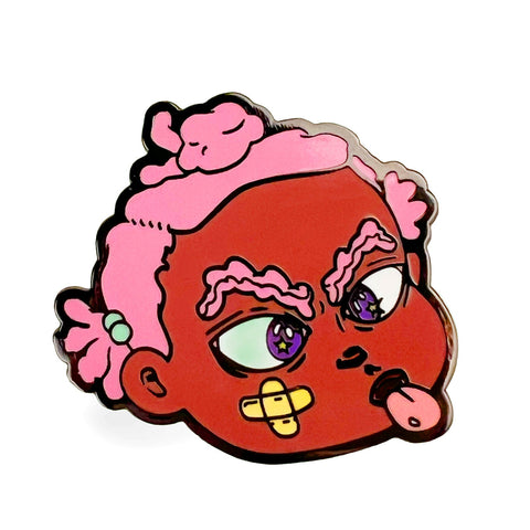 The Binky Tongue Out Hard Enamel Pin by Rotofugi features a red-faced character with pink hair, big eyebrows, a chin bandage, and tongue out—ideal for Bianca Pastel fans and lovers of Black female art.