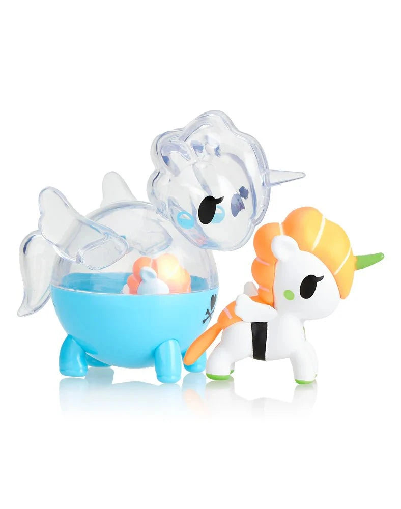 A small toy set from tokidoki's Unicorno Capsule Cuties Blind Box featuring a clear blue narwhal with a unicorn horn and a white and orange Unicorno figurine.