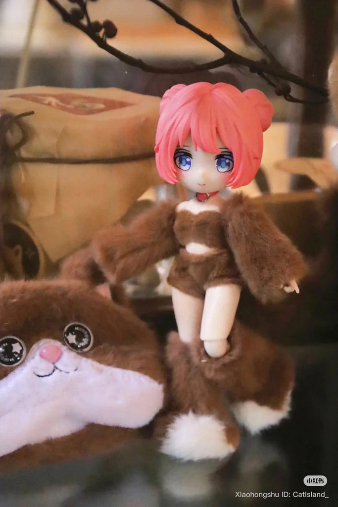 A BIJIDI Cat Island — Black Cat Or Candy Cat? Blind Box ball-jointed doll with pink hair and blue eyes, in a brown furry outfit, stands beside a matching cat-faced plush toy.