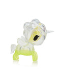 A small, translucent plastic unicorn figurine by tokidoki, inspired by the Toki Mochi Donut Unicorno Blind Bag, featuring a yellow body, white mane and tail, and a clear horn, shown in profile.