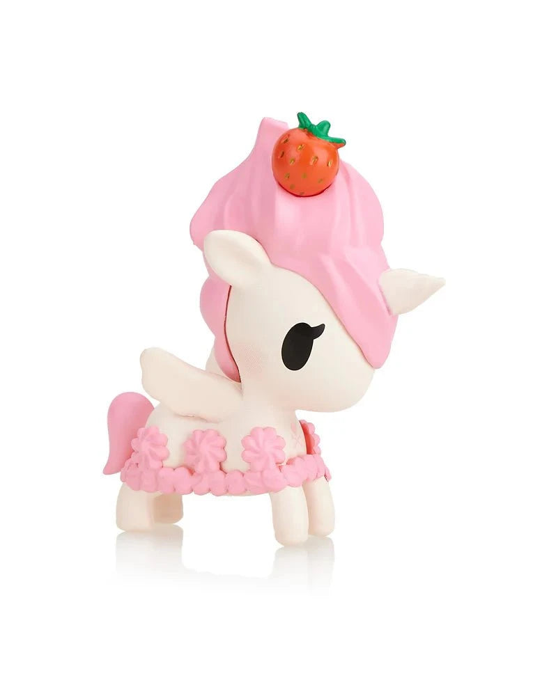 The tokidoki Toki Mochi Donut Unicorno Blind Bag features a small squishy Unicorno figurine with a pink mane, strawberry on its head, and pink flower decorations, shown against a white background.