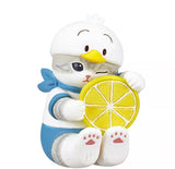 A Mofusand x Sanrio Series 2 Capsule figurine by Kitan Club features a winking kitty in a bird hat and blue costume, holding a yellow lemon slice against a white background.