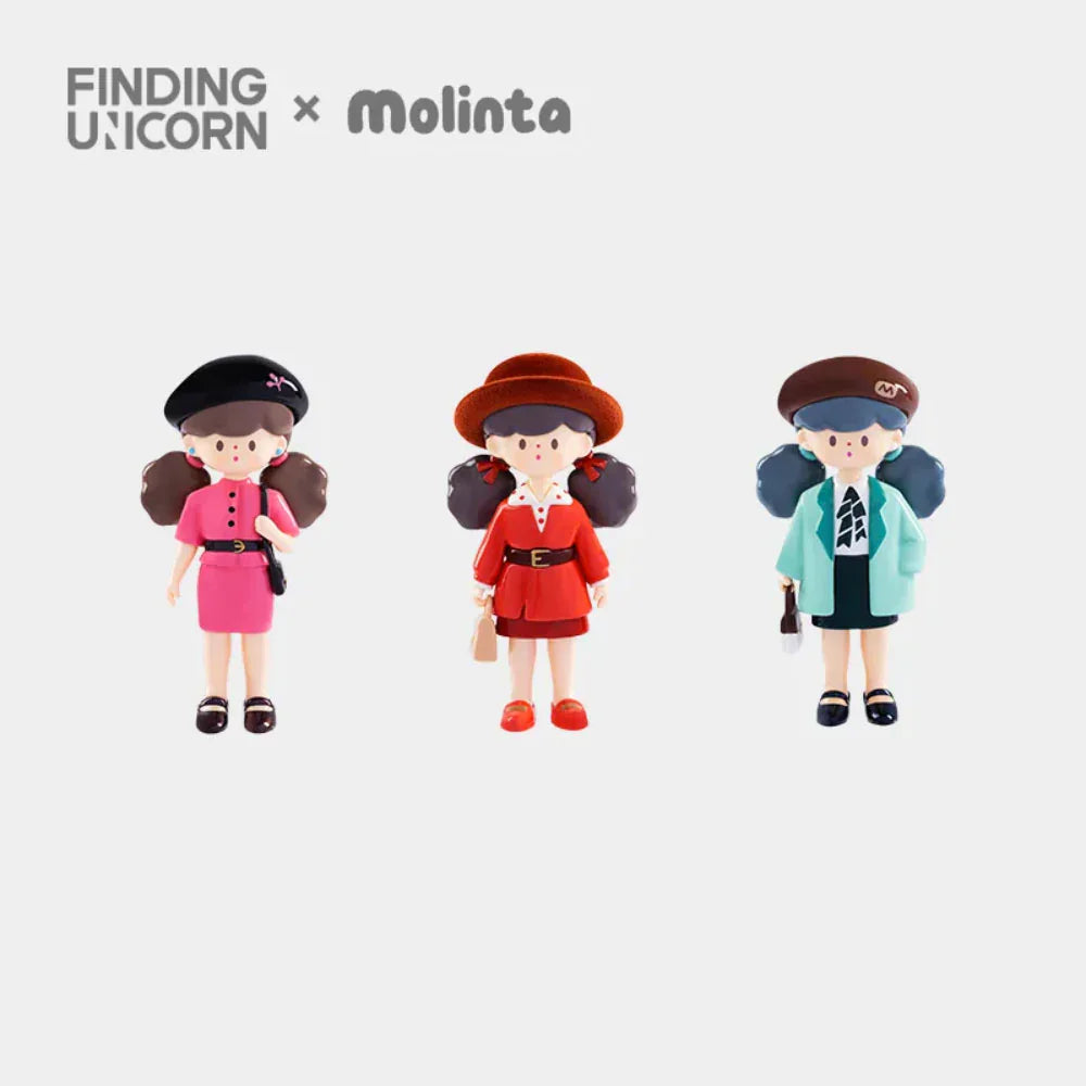 Three stylish girl figurines in pink, red, and teal outfits stand side by side against a white background. The