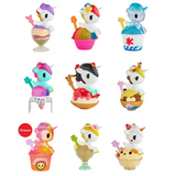 Nine vibrant unicorn figurines from the tokidoki Shaved Ice Dreams Unicorno Blind Box collection are perched in assorted ice cream and dessert-inspired cups and bowls, each holding a tiny star wand. Among these irresistible collectibles is the “Chaser” figurine in the bottom left corner, featuring a pink unicorn adorned with a rainbow-themed dessert.