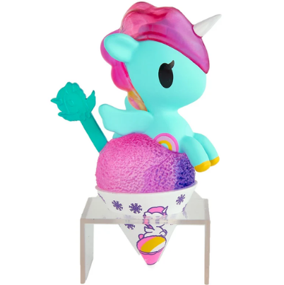 A delightful collectible from the tokidoki Shaved Ice Dreams Unicorno Blind Box series features a turquoise unicorn with pink hair and a white horn, sitting atop colorful shaved ice in a decorated cup and displayed on a small clear stand—perfect for any fan.