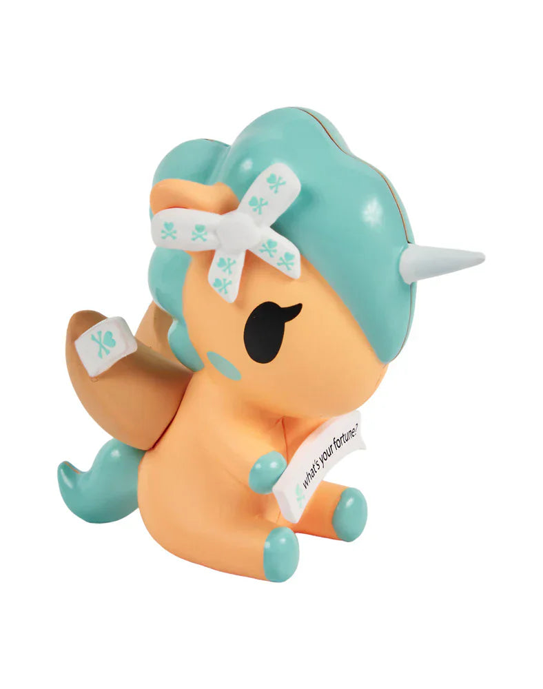 The tokidoki Fortune Cookie Unicorno Blind Box features a small orange and teal figurine with a fortune cookie theme, holding a fortune slip in its hooves—a delightful surprise collectible.