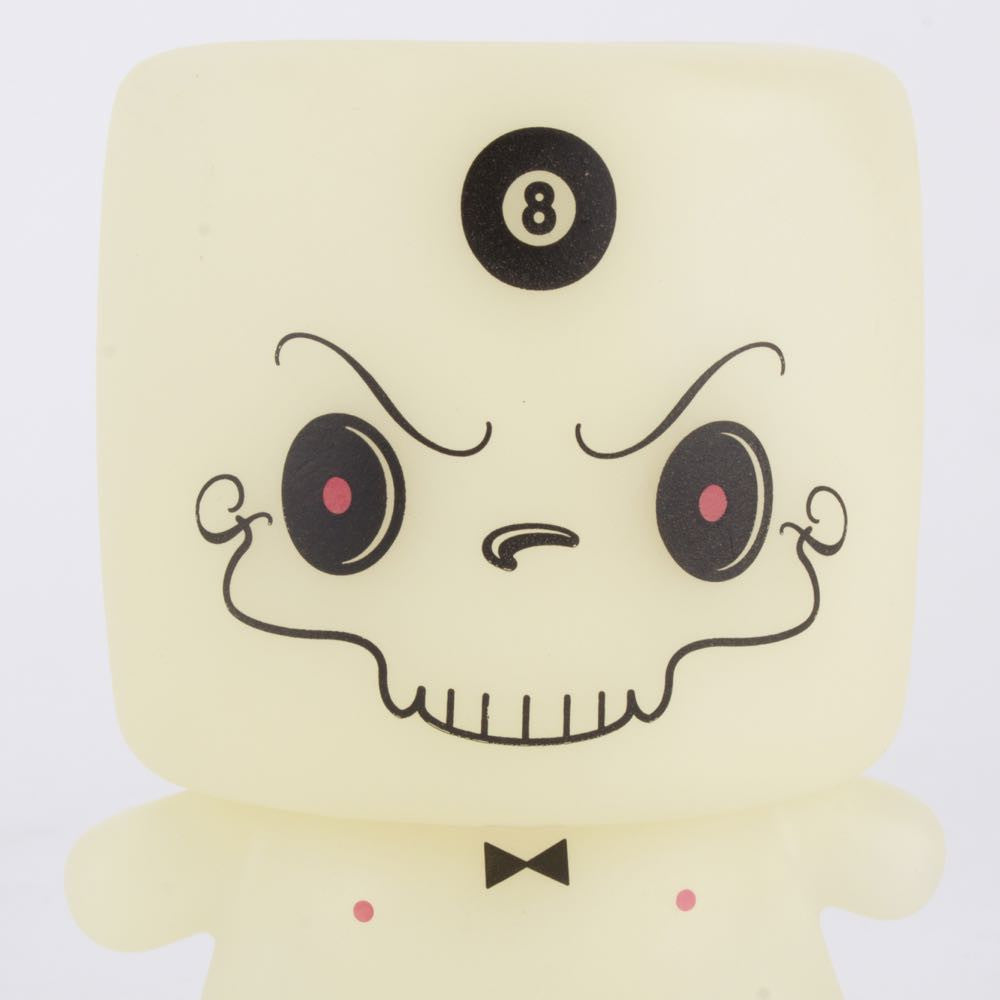 The limited edition Grim Marshall by 64 Colors from Squibbles Ink + Rotofugi is a vinyl toy with a square head, cartoonish angry face, black bow tie, and 8-ball on its forehead—perfect for collectors.