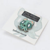 A limited edition enamel pin from The Artpin Collection – Octopup features a cartoon-style green creature with big eyes and small ears, mounted on a branded card by The Artpin Collection.
