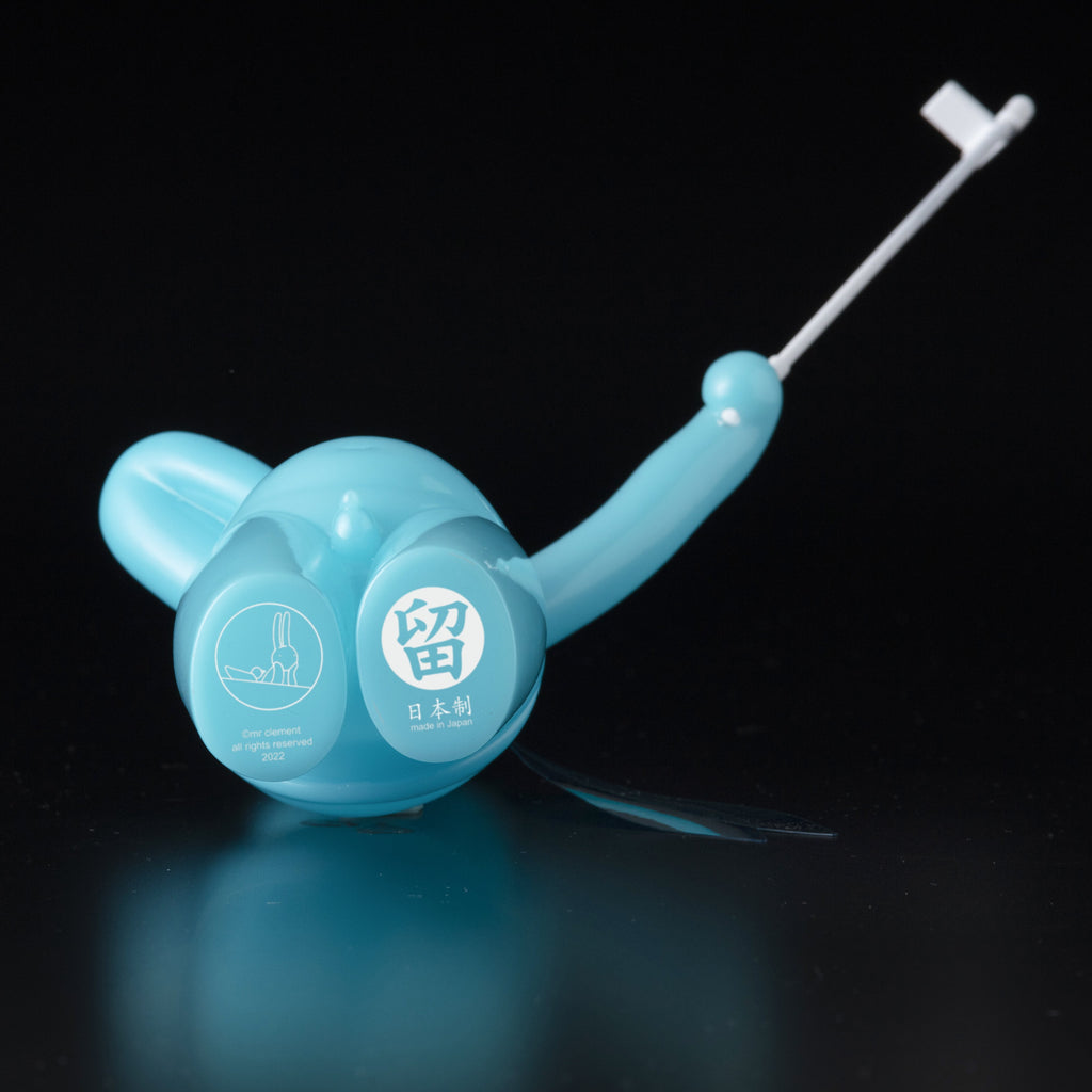 A blue plastic snail-shaped object with Japanese writing, a small snail graphic, and a white extendable handle. Shown against black, it’s The Daily Flasher by mr. clement from Tomenosuke Shoten, reminiscent of glow-in-the-dark vinyl toys.