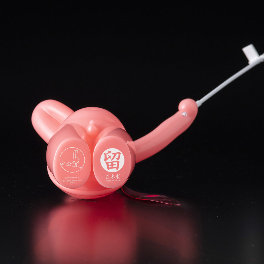 The Daily Flasher by mr. clement is a pink glow-in-the-dark balloon animal vinyl toy from Tomenosuke Shoten, shown on a black background with white Japanese text and a small graphic.