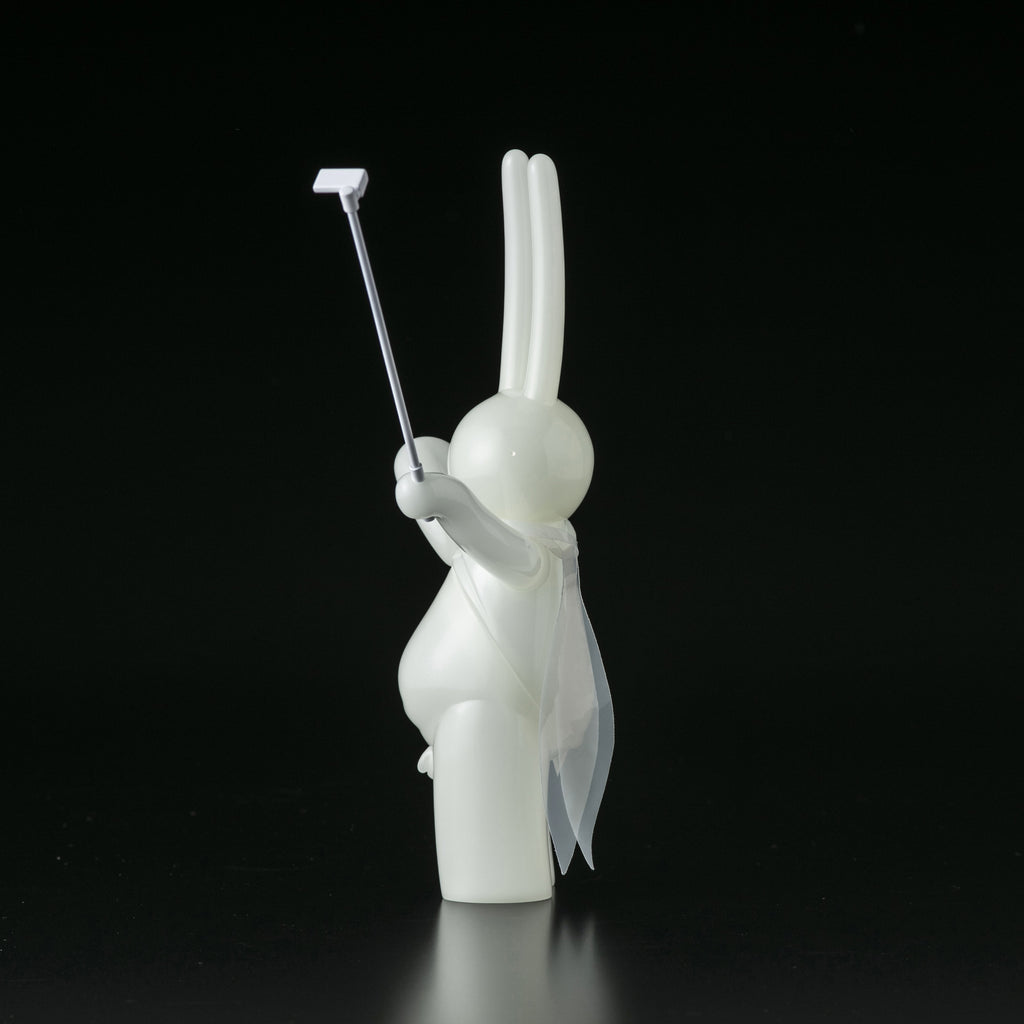 The Daily Flasher by mr. clement from Tomenosuke Shoten is a white rabbit sofubi figurine holding a selfie stick and wearing a sheer cape, posed against a plain black background.