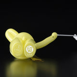 The Daily Flasher by mr. clement for Tomenosuke Shoten is a yellow plastic device with Japanese text, pictograms, a curved handle, and white cord, reflecting glow-in-the-dark vinyl toy culture. Photographed on a black background.