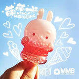 A hand holds the Meng Meng Bing — Bunny Popsicle Mini-Figure by Sun Day Toy, featuring a translucent bunny filled with pink and clear beads. White hearts, ice cream cones, and popsicles decorate the light blue background.