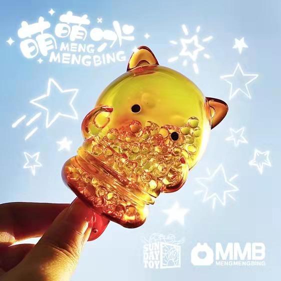 A hand holds the Sun Day Toy Meng Meng Bing — Dog Popsicle Mini-Figure, a translucent animal-shaped toy filled with beads, against a bright background with star illustrations and