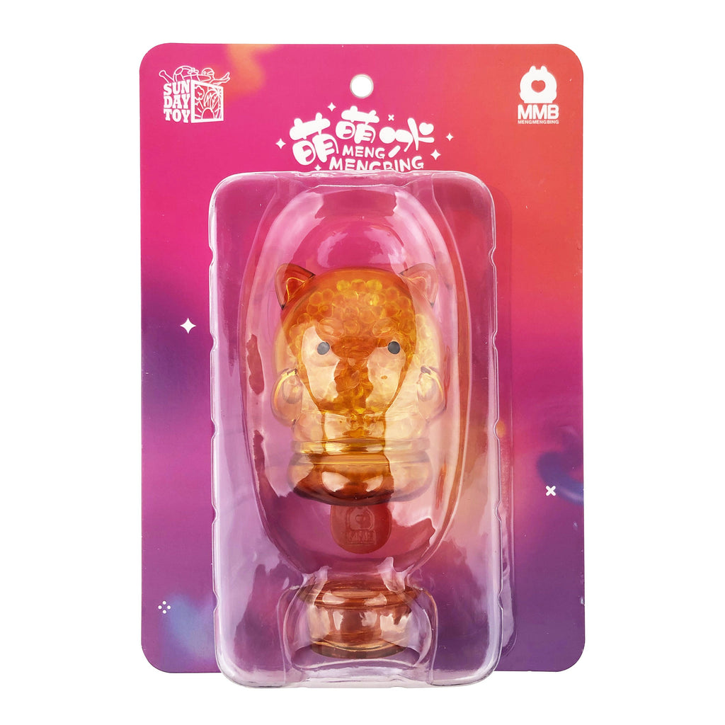 A small, amber-colored Meng Meng Bing — Dog Popsicle Mini-Figure from Sun Day Toy comes sealed in a clear blister pack with a colorful gradient backing featuring logos and text—perfect for fans of animal-shaped toys.