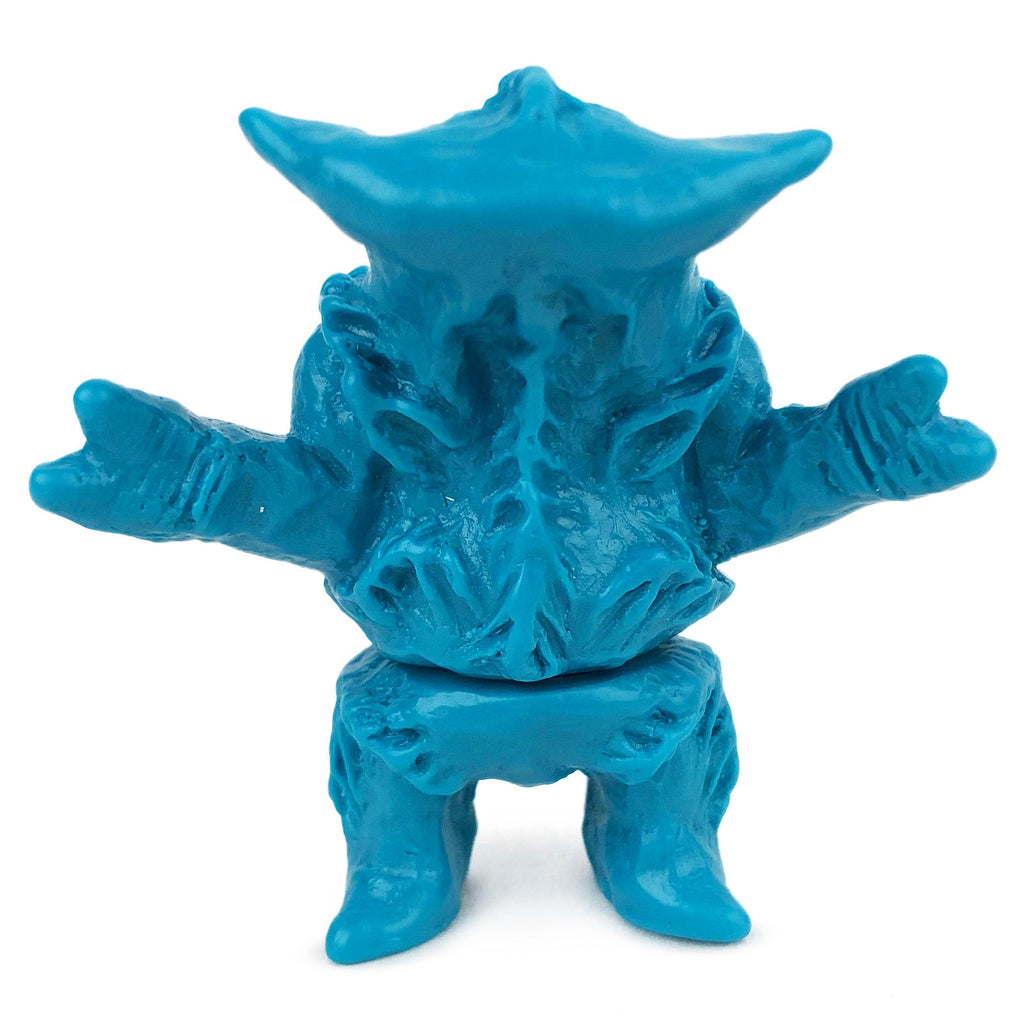 A small blue plastic figurine with horn-like features, outstretched arms, and a textured body—Geoff Maxfield’s Neo-Fighters X Rotofugi 312 Edition.