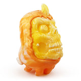 The Skully Ghost — Candy Corn by Squibbles Ink features orange and yellow colors, a skull-like face, small legs, a tail, and a single horn; it's photographed on a white background.