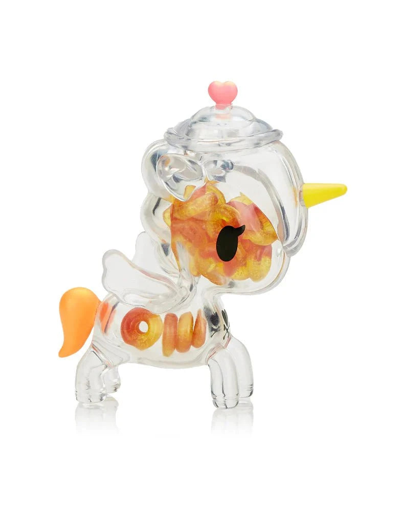 The tokidoki Sugar Shop Unicorno Blind Box features a transparent figure with orange/yellow details, yellow horn, white wings, and a heart-shaped knob—a delightful candy-themed collectible.