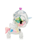 A tokidoki Sugar Shop Unicorno Blind Box figure—clear plastic with a blue horn, pink tail, and pastel beads inside—is seen in profile against a white background.