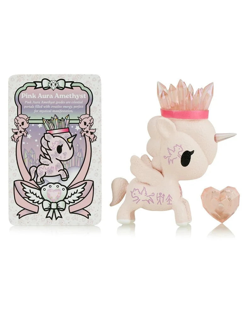 The tokidoki Precious Unicorno - Pink Aura Amethyst (Special Edition) features a pink unicorn figurine with a crystal crown, a heart-shaped gem, and a 