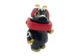 Akabegon- Black by Teresa Chiba is a black vinyl figure with gold accents, a red scarf, and wide yellow eyes. This stylized animal-like design stands upright and is considered a good luck charm.