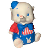 The Bitter Squeaks Carnival Stripes Baby Elephant plush toy wears a blue hat, red shirt, blue bow tie, striped vest, and bunny-themed blue overalls, shown sitting upright against a white background.