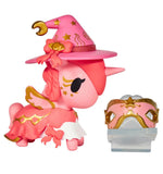 The tokidoki Unicorno After Dark Masquerade Blind Box features a pink unicorn figurine with gold wings and a wizard hat, standing next to a matching pink and gold mask on a stand—a magical collectible toy.