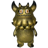 The Little Hut’s Rangeas Jr. - Gold Patina figure features gold horns, wide eyes, pointed teeth, clawed hands, and a bumpy chest—an eye-catching collectible monster standing upright against a white background.