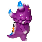 Side view of The Little Hut’s Rangeas Jr. - Purple monster figurine with blue-tipped horns, orange eye, spiked tail, and bumpy collar, standing upright against a white background—a must-have collectible toy.