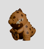 A brown, cartoon-style dinosaur figurine with dark spots and a grumpy face from the Kaiju Cookies Blind Box by Kaleidos Creative sits on its haunches, resembling a cute collectible against a plain background.