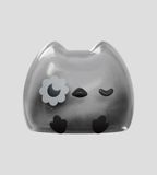 Kairos the Owl Blind Box by Kaleidos Creative features a transparent, cat-shaped owl with a flower eye patch, closed eyes, and simple black details on a light gray background—a whimsical must-have for any blind box collector.