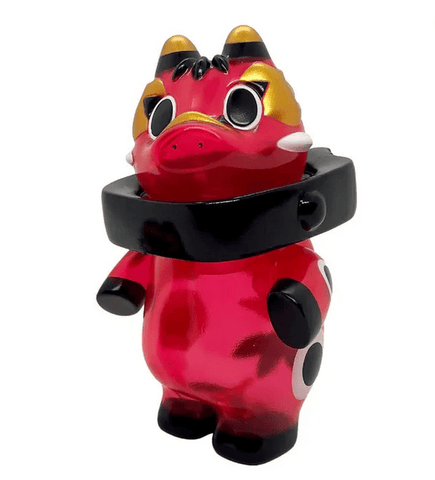 The Akabegon- Clear Red by Teresa Chiba is a red and black cartoon-style figurine with gold accents, large eyes, and a thick black collar, standing on two legs as a playful good luck charm.