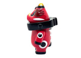 The Akabegon-Red by Teresa Chiba is a red figurine with black and white details, yellow-tipped ears, and a black collar, standing upright like a folklore cow against a white background.