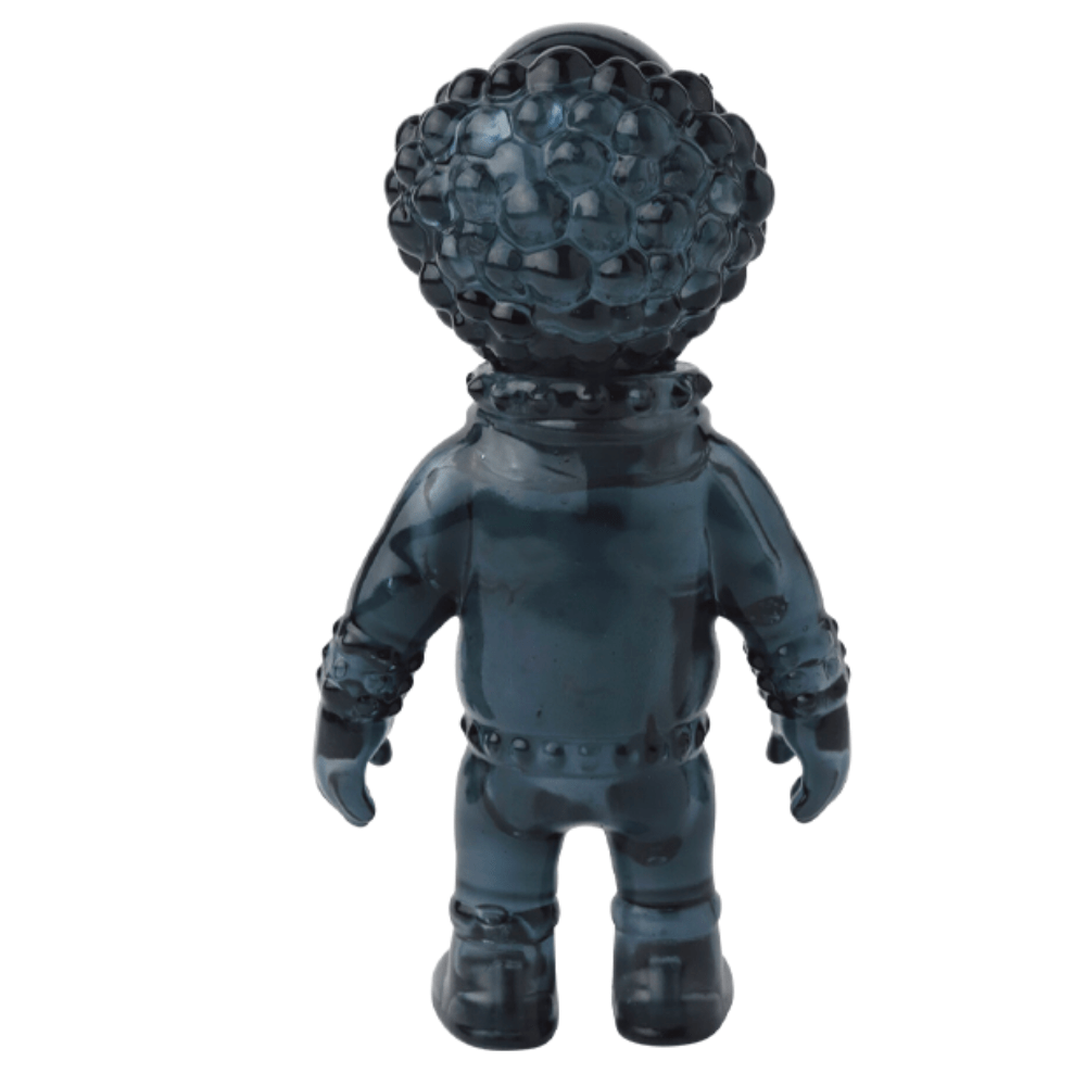 A black, glossy VAG 36 - Deadman vinyl figure by Medicom, featuring a textured head and spacesuit-like body, stands with its back to the viewer against a white background—evoking collectible gachapon figures.