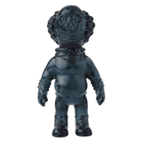 The Medicom VAG 36 - Deadman is a dark, glossy humanoid figurine with exaggerated features and large textured hair, reminiscent of collectible Japanese vinyl gachapon toys. It stands upright with detailed wrists and neck against a white background.