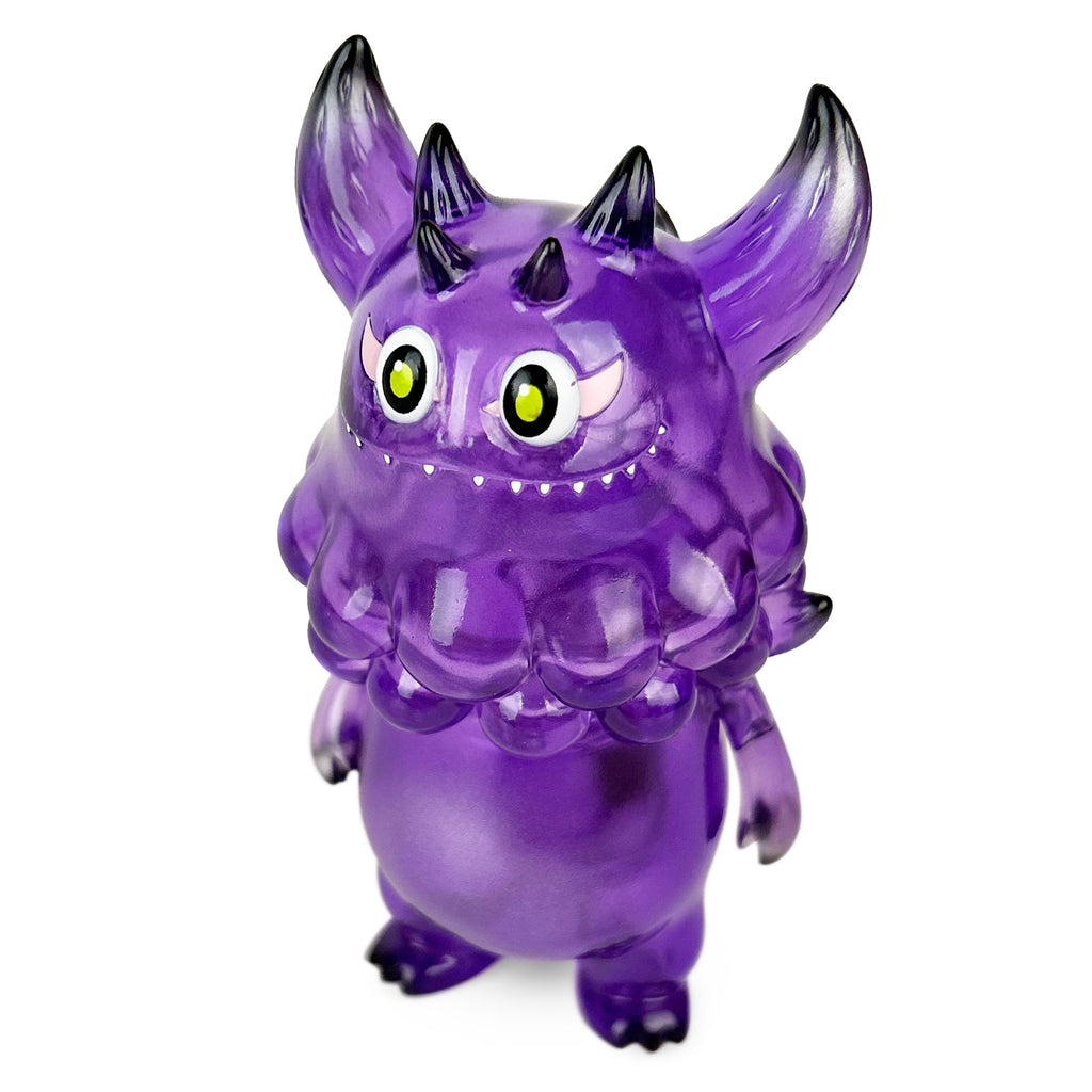 Rangeas Jr. — Clear Purple by The Little Hut is a translucent purple toy monster with large yellow eyes, two horns, pointed ears, and small back spikes, shown standing upright against a white background.